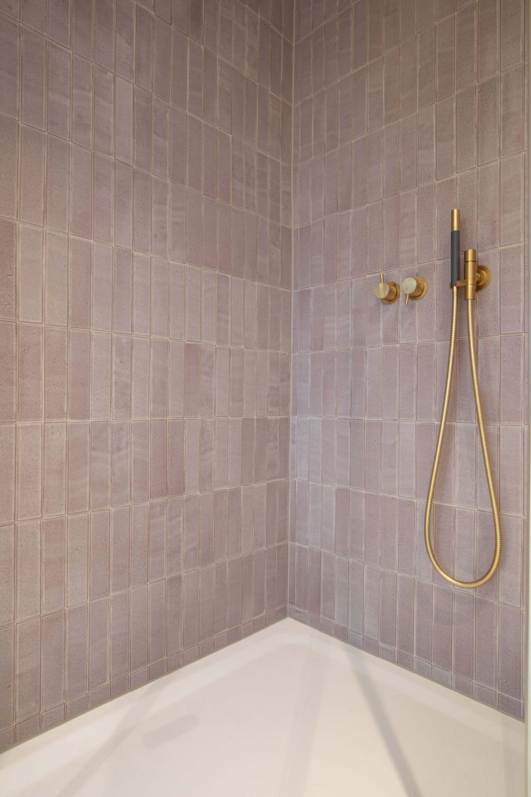 Glänzende Wandplatten stehend in einer Dusche verlegt.